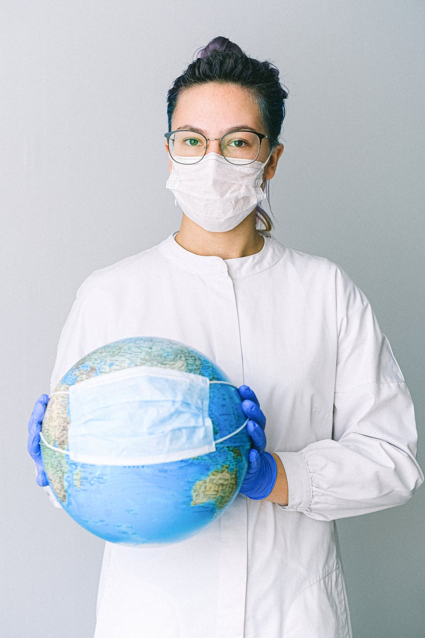 photo of person wearing protective wear while holding globe